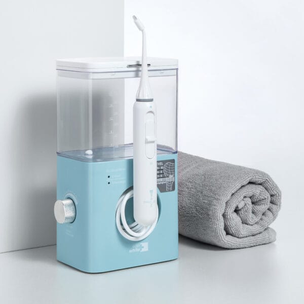 edel+white Flosserpik Pro Station - puissante douche buccale avec 10 niveaux de pression, 2 modes et 4 embouts pour un soin minutieux des dents et des gencives. Illustration produit avec serviette à côté.
